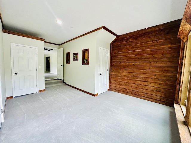 unfurnished room featuring wood walls, ceiling fan, and ornamental molding