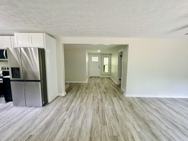 kitchen with white cabinets, stainless steel appliances, a textured ceiling, and light hardwood / wood-style floors