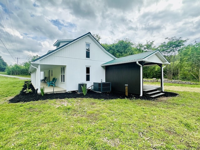 back of property with a yard and central AC