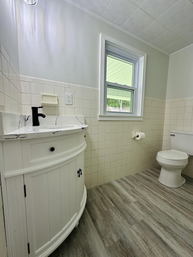 bathroom featuring crown molding, toilet, vanity, tile walls, and hardwood / wood-style flooring