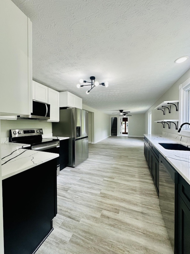 kitchen with white cabinets, sink, light stone countertops, light wood-type flooring, and stainless steel appliances