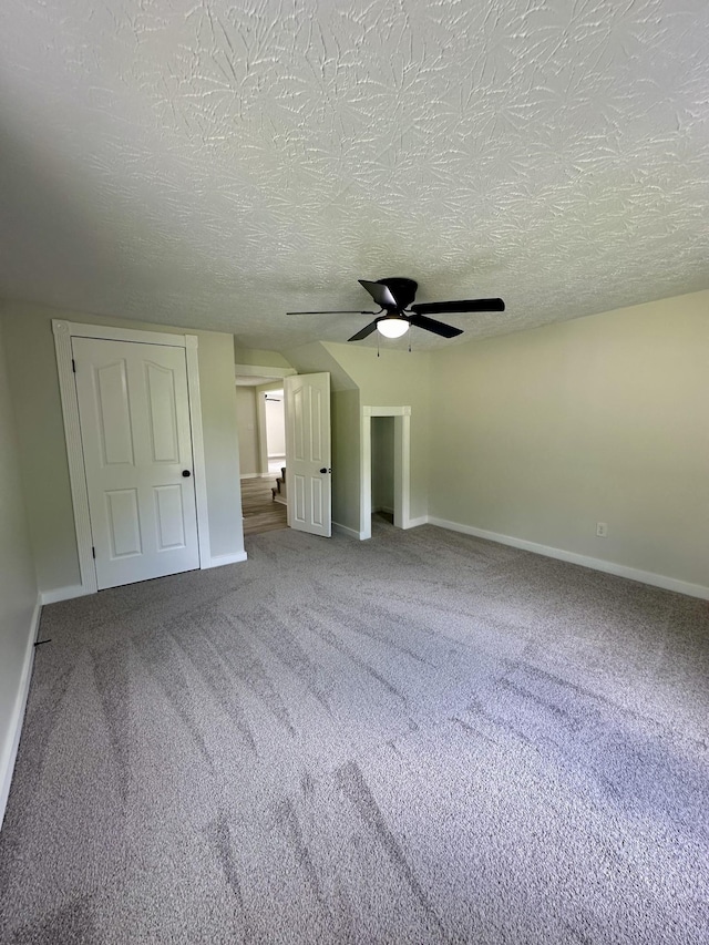 unfurnished bedroom featuring carpet, a textured ceiling, and ceiling fan