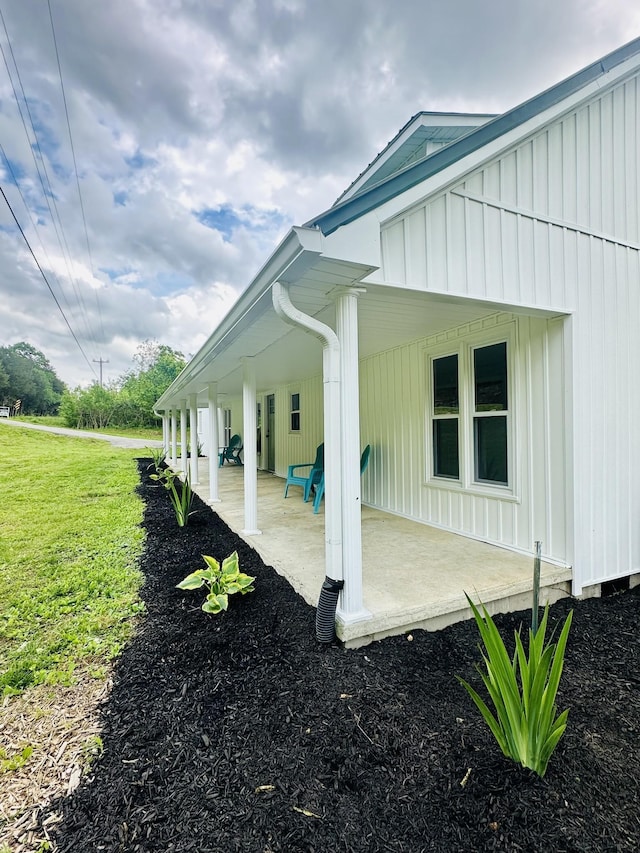 view of side of property with a yard and covered porch