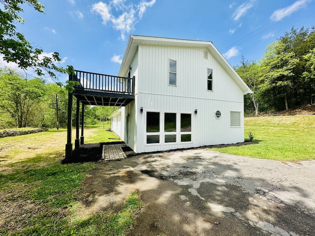 back of property featuring a lawn and a wooden deck