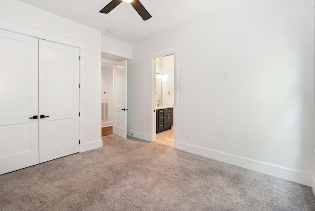 unfurnished bedroom featuring sink, ceiling fan, connected bathroom, light colored carpet, and a closet