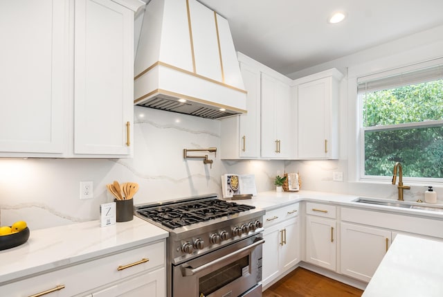 kitchen with decorative backsplash, high end stove, premium range hood, and white cabinetry