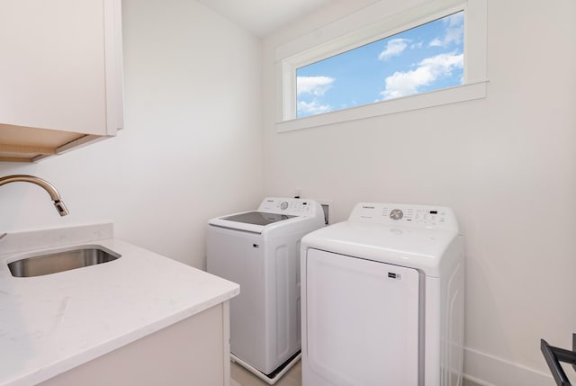 clothes washing area with cabinets, separate washer and dryer, and sink