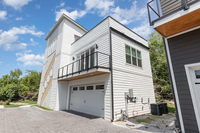 view of home's exterior with a garage, a balcony, and central AC