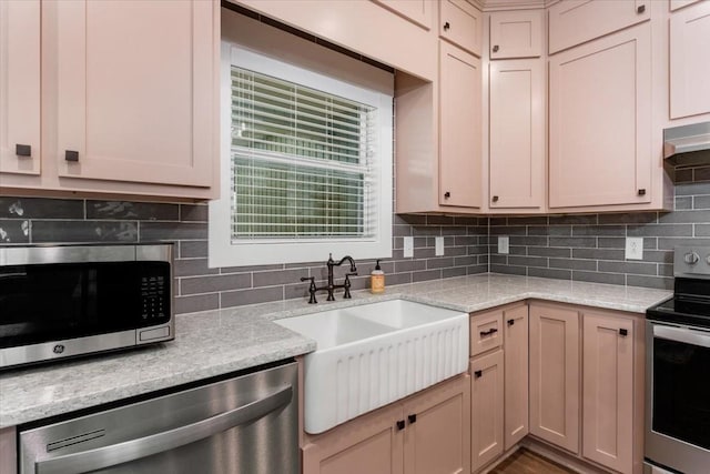 kitchen featuring light stone countertops, appliances with stainless steel finishes, tasteful backsplash, and sink