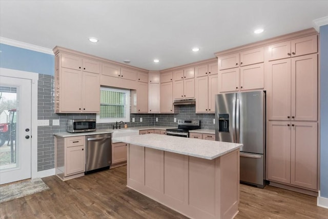 kitchen with a center island, dark wood-type flooring, crown molding, decorative backsplash, and stainless steel appliances