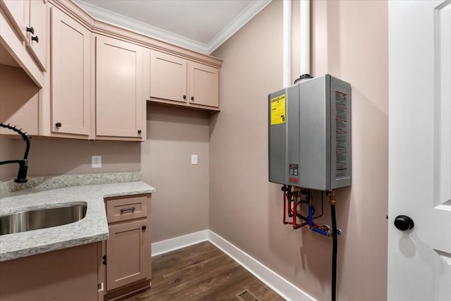 clothes washing area with dark hardwood / wood-style flooring, tankless water heater, ornamental molding, and sink