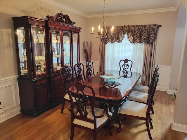 dining space with hardwood / wood-style flooring, ornamental molding, and a chandelier