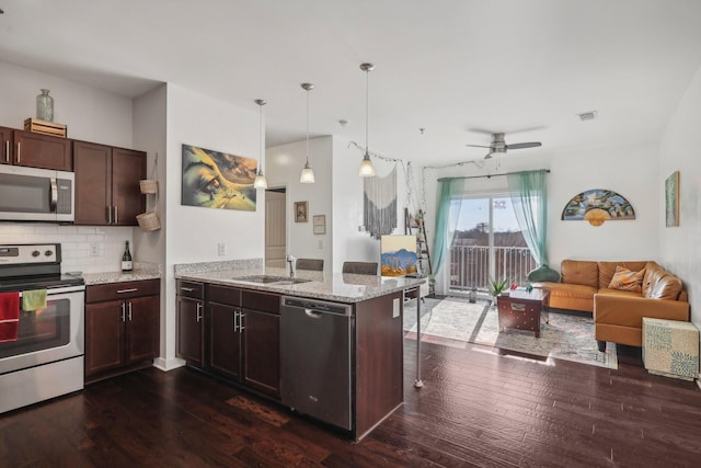 kitchen featuring kitchen peninsula, appliances with stainless steel finishes, decorative light fixtures, and dark wood-type flooring