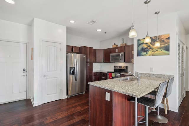 kitchen with a breakfast bar area, kitchen peninsula, dark hardwood / wood-style flooring, and appliances with stainless steel finishes