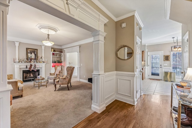 living area featuring hardwood / wood-style flooring, ornate columns, and crown molding