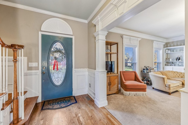 entrance foyer with decorative columns, wood-type flooring, and ornamental molding