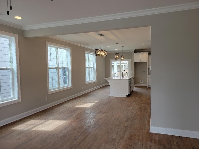 kitchen featuring hardwood / wood-style floors, white cabinetry, a center island with sink, and hanging light fixtures