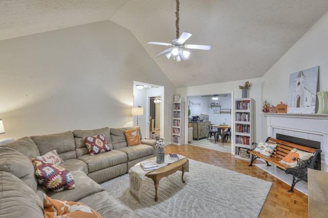 living room featuring a tiled fireplace, ceiling fan, light parquet floors, and a textured ceiling