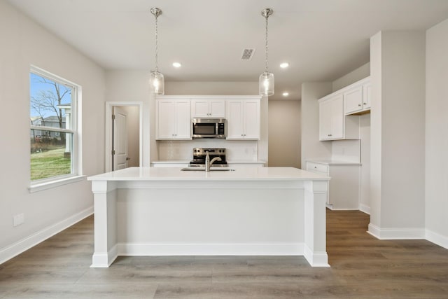 kitchen featuring sink, white cabinetry, stainless steel appliances, and a kitchen island with sink