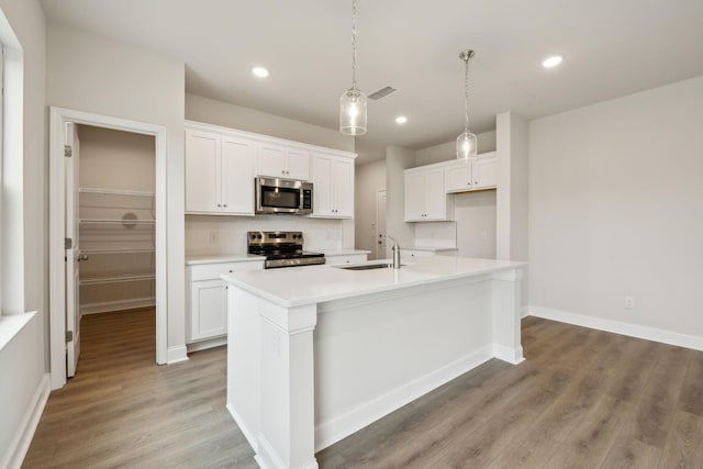 kitchen featuring white cabinets, an island with sink, and stainless steel appliances