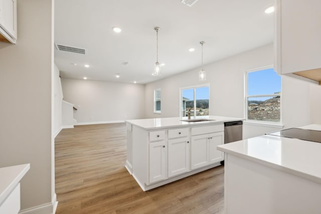 kitchen featuring dishwasher, sink, hanging light fixtures, an island with sink, and white cabinetry