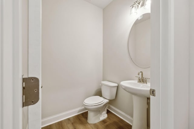 bathroom with wood-type flooring, toilet, and sink