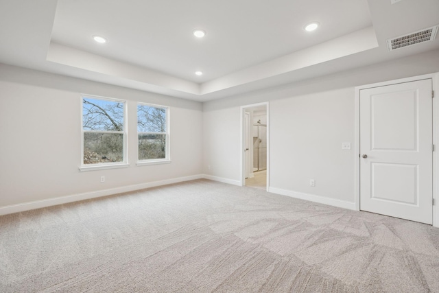 unfurnished room with a tray ceiling and light colored carpet