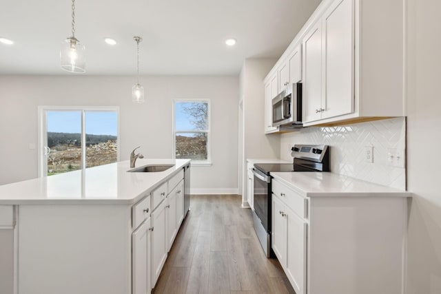 kitchen featuring sink, white cabinets, decorative light fixtures, and appliances with stainless steel finishes