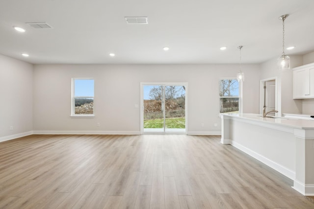 unfurnished living room with sink and light hardwood / wood-style flooring