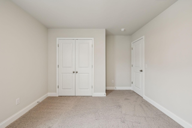 unfurnished bedroom featuring light colored carpet and a closet