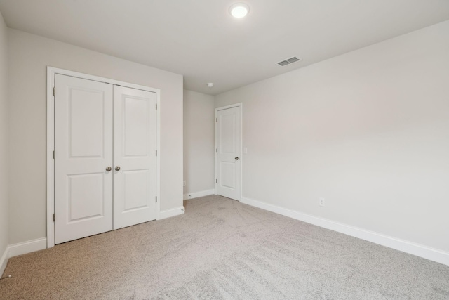 unfurnished bedroom featuring light colored carpet and a closet