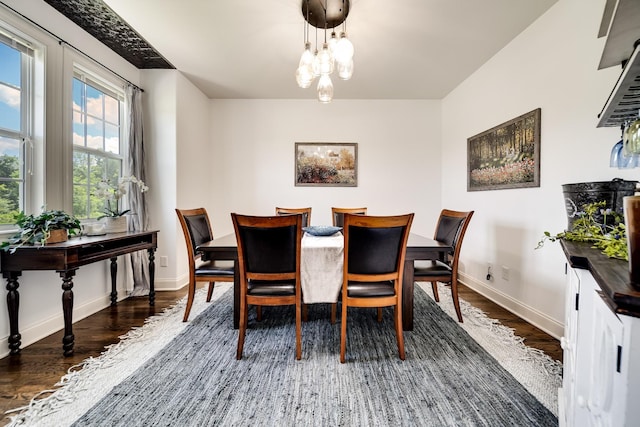 dining area featuring dark wood-type flooring and an inviting chandelier