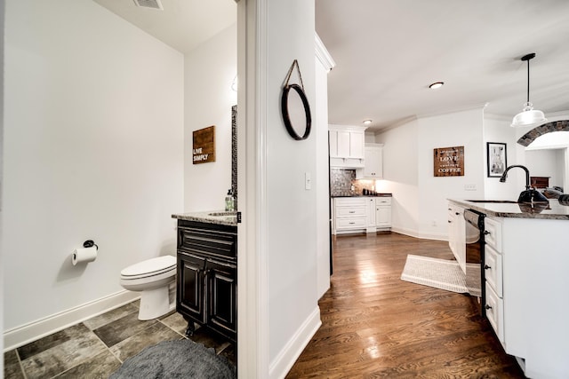 kitchen with pendant lighting, dark stone counters, sink, decorative backsplash, and dark hardwood / wood-style flooring