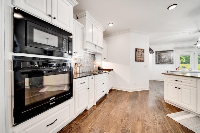 kitchen featuring dark stone counters, crown molding, black appliances, hardwood / wood-style flooring, and white cabinetry