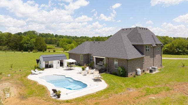 view of pool with central air condition unit, a storage unit, a patio area, and a lawn