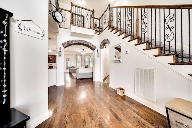 foyer entrance with a towering ceiling, hardwood / wood-style flooring, and ceiling fan