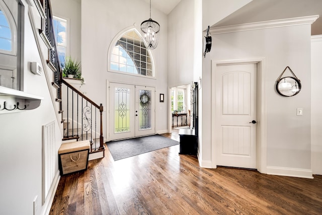 entrance foyer with a notable chandelier, crown molding, dark wood-type flooring, and a high ceiling