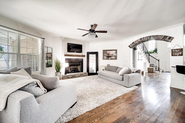 living room featuring crown molding, dark hardwood / wood-style floors, and a brick fireplace