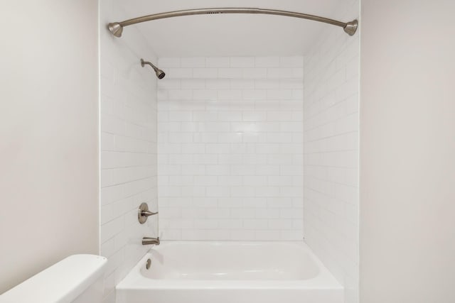 bathroom with tiled shower / bath combo and toilet