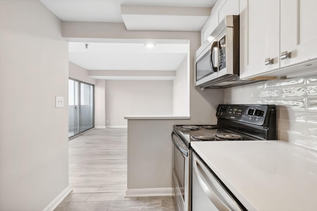 kitchen with backsplash, stainless steel appliances, white cabinetry, and light hardwood / wood-style flooring