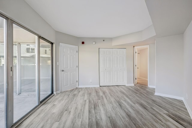 unfurnished bedroom featuring access to outside, a closet, and light hardwood / wood-style floors