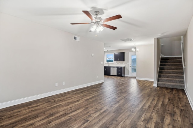 unfurnished living room featuring ceiling fan with notable chandelier and dark hardwood / wood-style floors