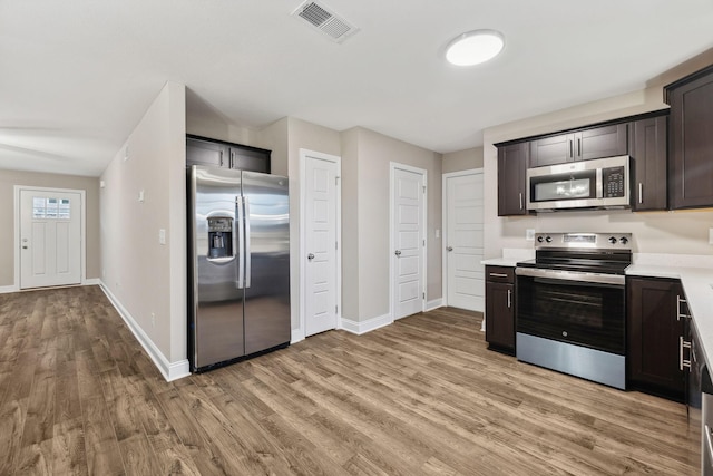 kitchen with dark brown cabinets, appliances with stainless steel finishes, and light hardwood / wood-style flooring