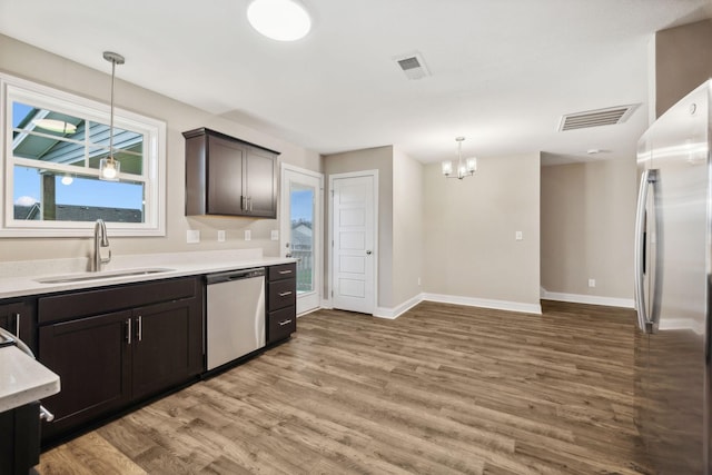 kitchen featuring sink, hardwood / wood-style flooring, dark brown cabinetry, stainless steel appliances, and a chandelier