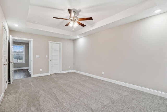 carpeted empty room with a tray ceiling and ceiling fan