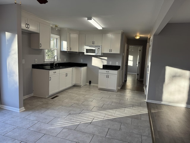 kitchen with light hardwood / wood-style flooring, white cabinetry, ceiling fan, and sink