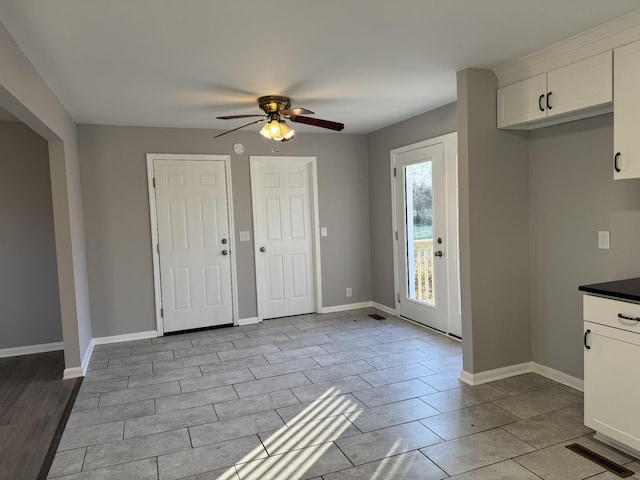 interior space featuring white cabinets, ceiling fan, and light tile patterned flooring