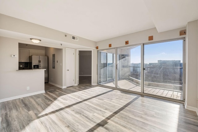 spare room featuring electric panel and light hardwood / wood-style flooring