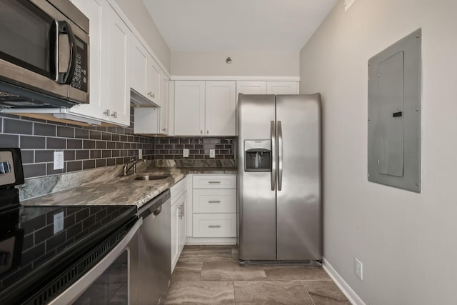 kitchen with white cabinets, electric panel, dark stone countertops, and appliances with stainless steel finishes