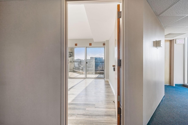 corridor with a drop ceiling and light wood-type flooring